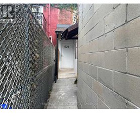 A narrow alley with a white door and a brick wall on the right.