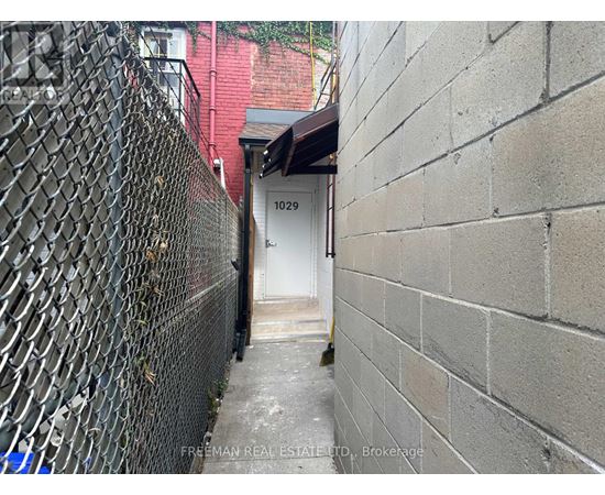 A narrow alley with a white door and a brick wall on the right.