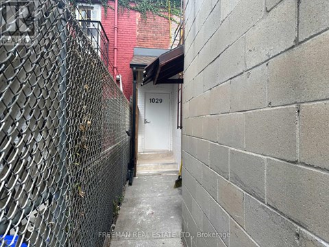 A narrow alley with a white door and a brick wall on the right.
