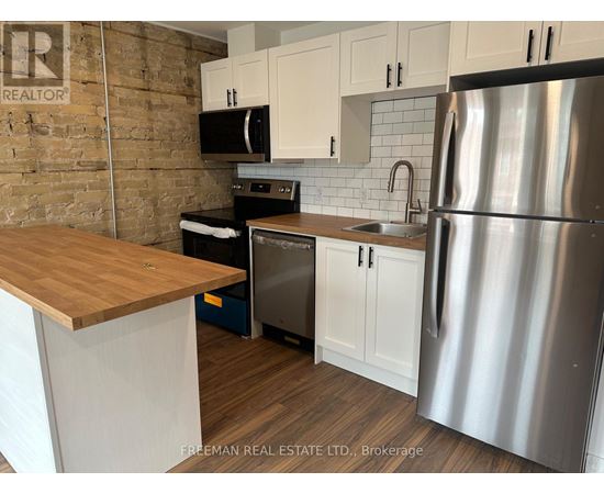 A kitchen with a wooden counter top and stainless steel appliances.