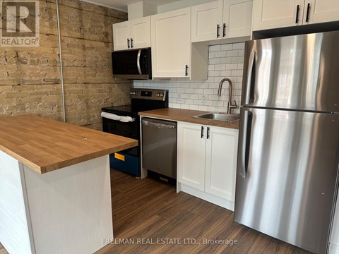 A kitchen with a wooden counter top and stainless steel appliances.