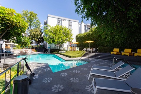 A pool surrounded by trees and chairs.