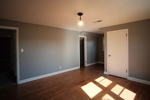 A room with a light on the ceiling and sunlight coming through the windows.