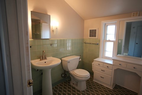 A bathroom with a toilet, sink, and mirror.