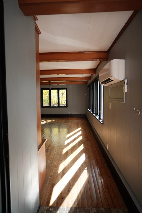 A long hallway with wooden floors and a window letting in sunlight.