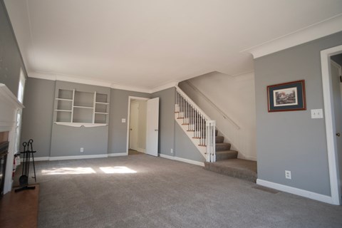 A living room with a staircase leading to the second floor.
