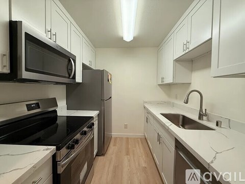 A kitchen with black and white appliances and wooden floors.
