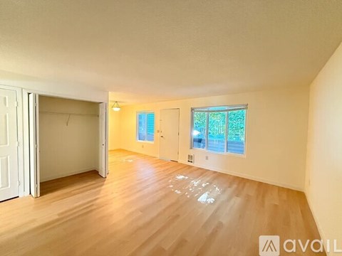 A room with wooden flooring and a window with a view of trees.