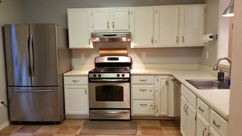 A kitchen with white cabinets and a stainless steel refrigerator.
