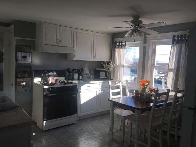 A kitchen with a table and chairs by a window.