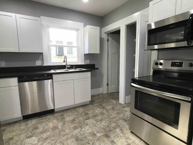 A kitchen with white cabinets and a black countertop.