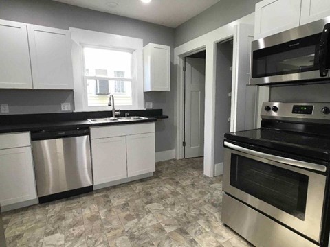 A kitchen with white cabinets and a black countertop.