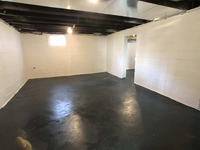 A spacious empty room with a black floor and white walls.