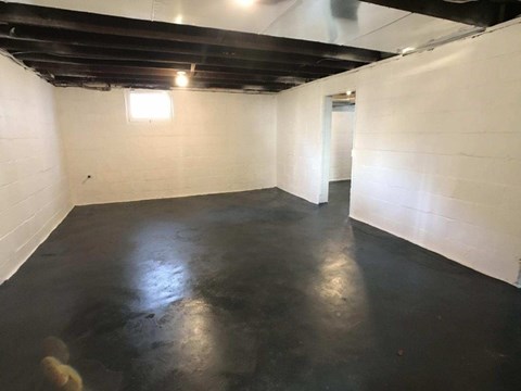 A spacious empty room with a black floor and white walls.