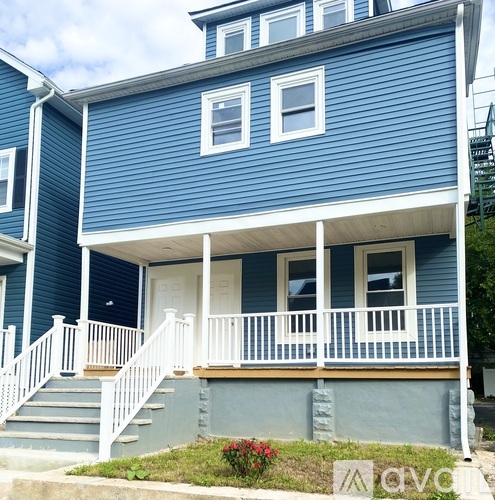 A blue house with white railings and a white door.