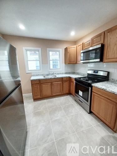 A kitchen with wooden cabinets and a stainless steel refrigerator.