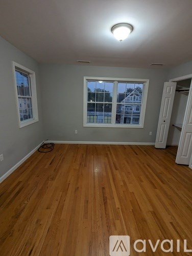 A room with wooden flooring and a window overlooking a building.