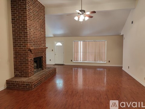 A room with a brick fireplace and wooden floors.