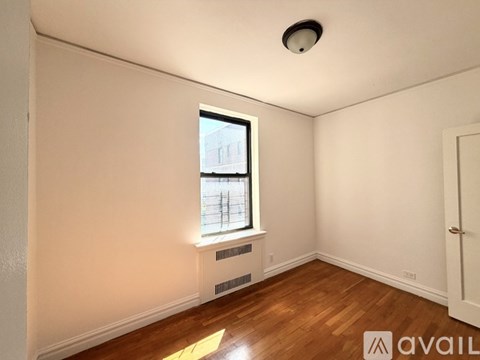 A room with a window and wooden floors is available for rent.