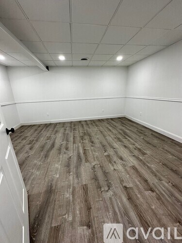 A room with wooden flooring and white walls.