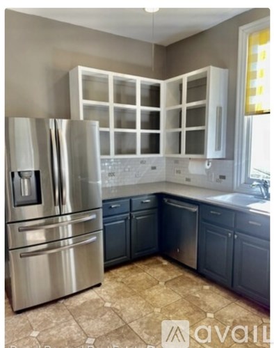 A kitchen with a stainless steel refrigerator and cabinets.