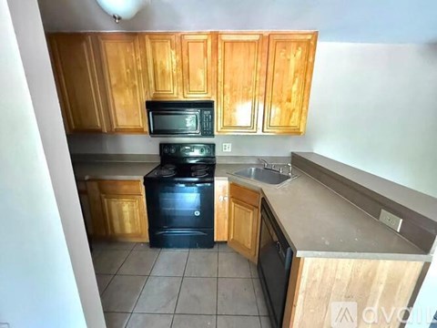A kitchen with wooden cabinets and black appliances.