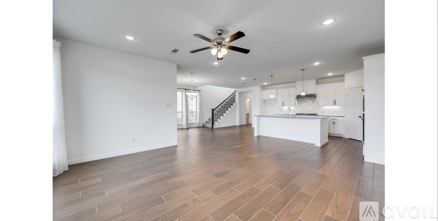 A spacious room with a ceiling fan and wooden flooring.