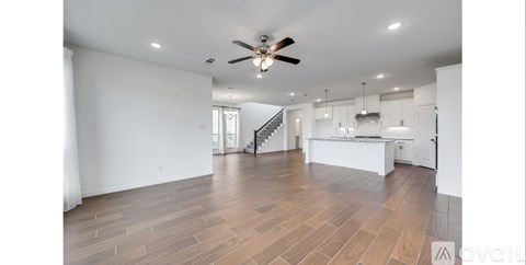 A spacious room with a ceiling fan and wooden flooring.
