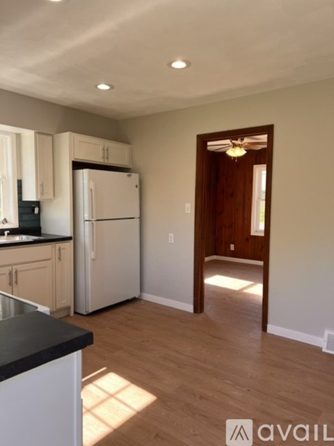 A kitchen with white appliances and wooden floors.
