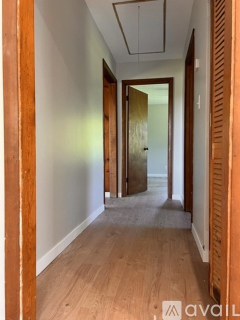 A hallway with wooden floors and white walls.