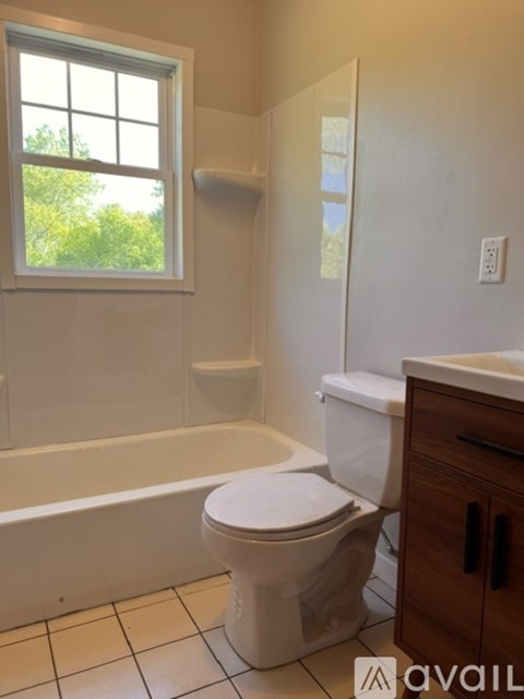 A white toilet in a bathroom with a window.