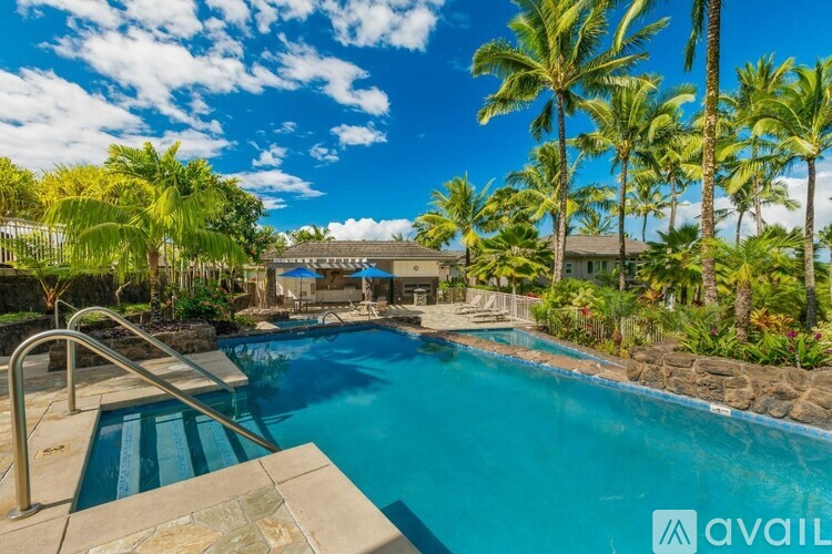 A pool surrounded by palm trees and a stone wall.