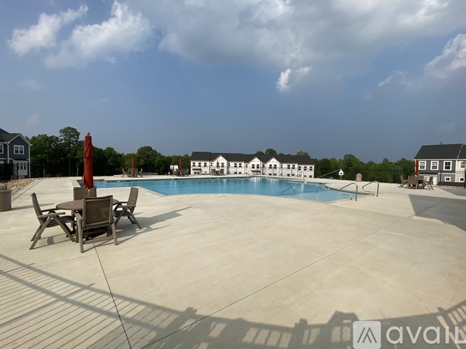 A pool with a table and chairs in front of a house.