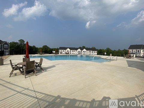 A pool with a table and chairs in front of a house.