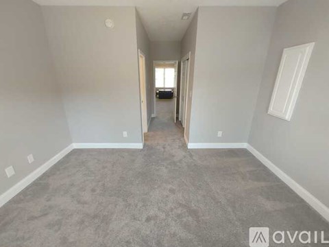 A spacious room with grey carpeting and white walls.