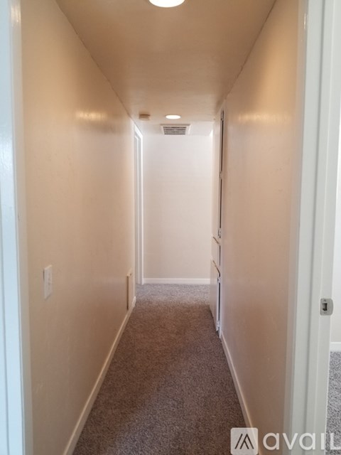A long hallway with carpeted flooring and white walls.