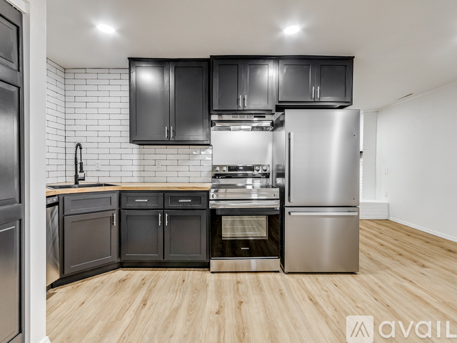 A modern kitchen with black cabinets and stainless steel appliances.