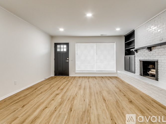 A spacious room with wooden flooring and a fireplace.