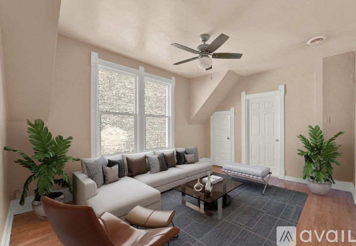 A living room with a large couch, a chair, a coffee table, and a ceiling fan.