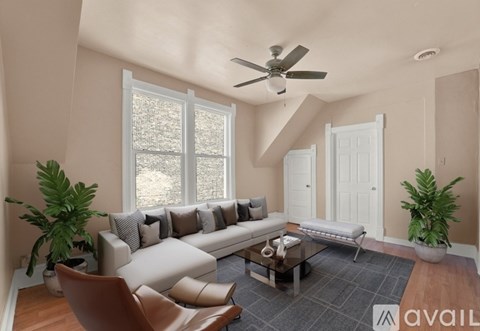 A living room with a large couch, a chair, a coffee table, and a ceiling fan.