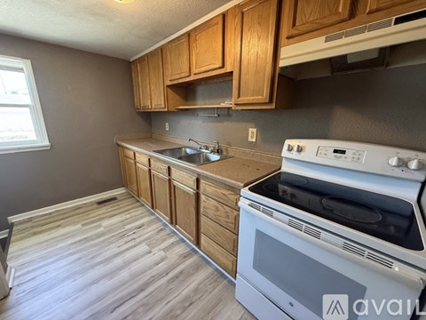 A kitchen with a white stove top oven and wooden cabinets.