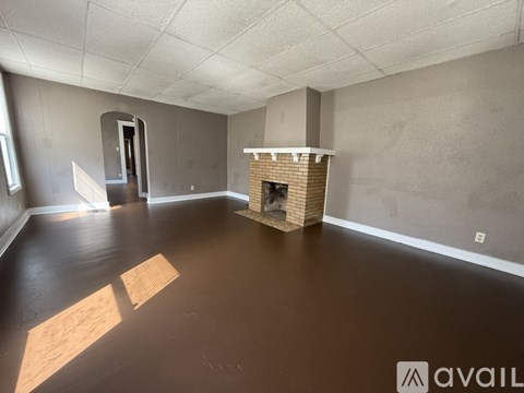 A room with a fireplace and a doorway leading to another room.