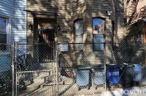 A dilapidated building with a broken window and a fence in front.