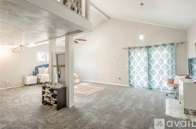 A spacious living room with a grey carpet and a ceiling fan.