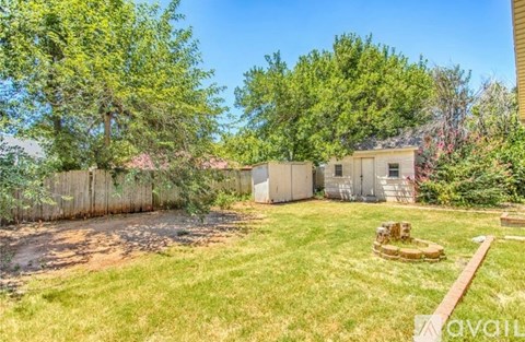 A backyard with a fence, trees, and a small shed.