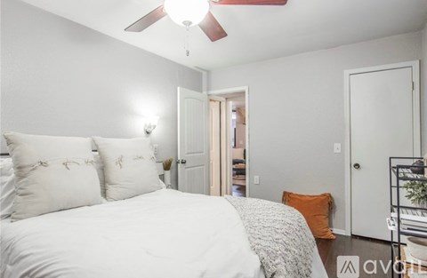 A bedroom with a white bed and a ceiling fan.