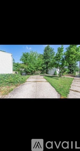 A residential street with a house on the left and trees on the right.