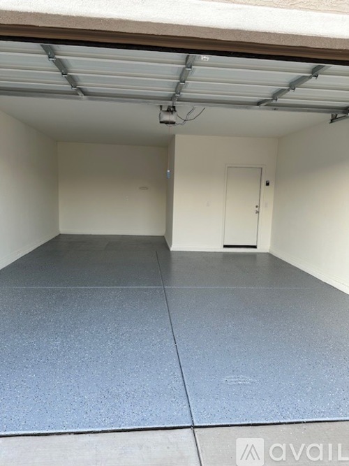 A spacious garage with a grey floor and a white door.