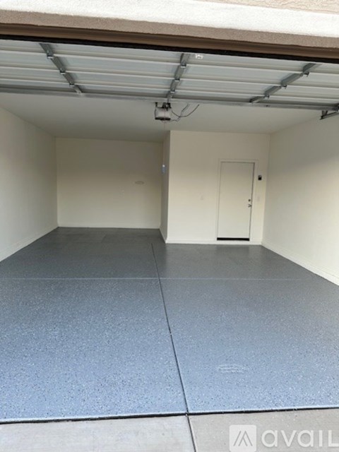A spacious garage with a grey floor and a white door.