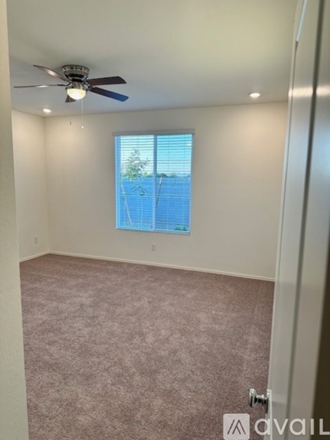 A room with a ceiling fan and carpeted floor.